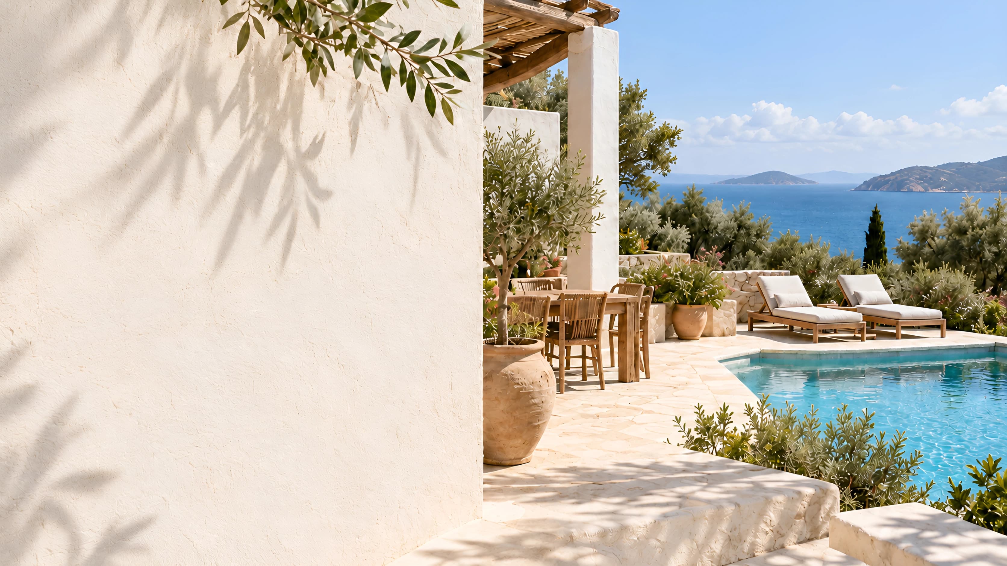 A sunlit villa terrace: olive branches and their shadows across a plaster wall, a stone table, two sun loungers and a pool above the sea